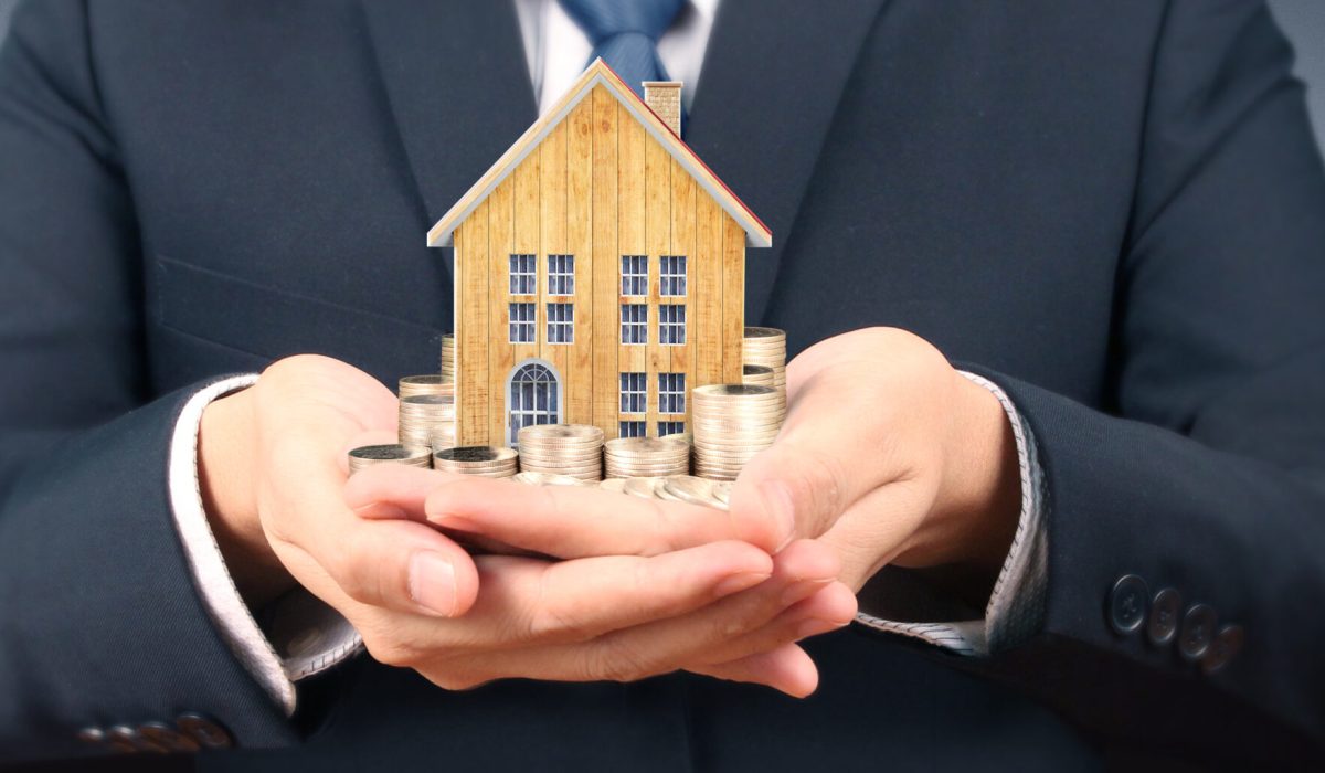 Growing coins house on stack coins in hand. Concept of Investment propert and finance investment concep